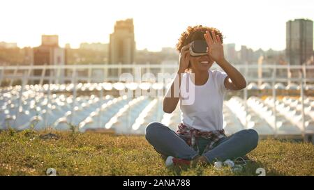 Curly haired lady using virtual reality glasses, touching air, modern technology Stock Photo
