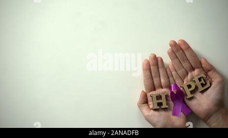 Purple ribbon in woman hands, epilepsy awareness and prevention campaign, care Stock Photo
