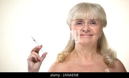 Aged lady holding syringe with insulin, diabetes prevention, timely diagnostics Stock Photo