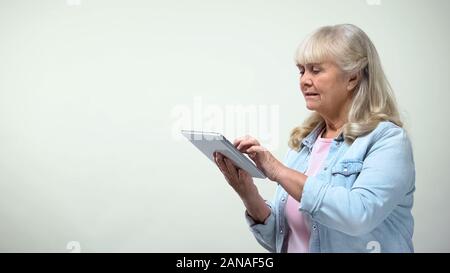 Aged woman using application on tablet for online shopping, modern technologies Stock Photo