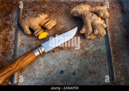Ginger , cut and whole with knife on rustic background. Stock Photo