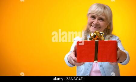 Optimistic senior lady showing present to camera, preparation for holidays Stock Photo