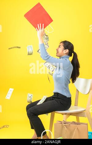 The woman raised the red paper bag and poured out the money into her head. Stock Photo