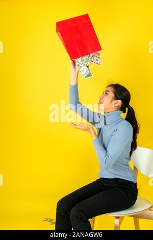 The woman raised the red paper bag and poured out the money into her head. Stock Photo