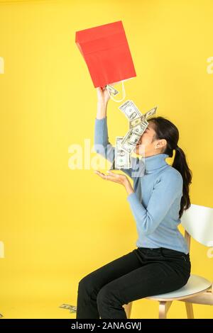 The woman raised the red paper bag and poured out the money into her face. Stock Photo