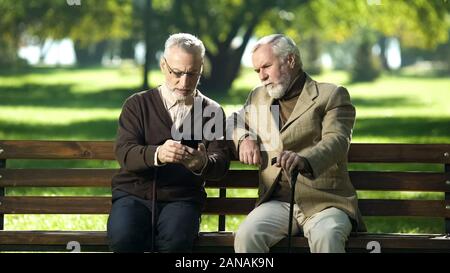 Elderly man asking friend for help with smart phone, new modern technologies Stock Photo
