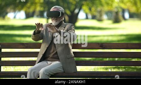 Amazed senior men using VR headset outdoors, modern technologies experience Stock Photo