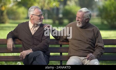 Elderly male friends smoking cigar, friends enjoying rest in park together Stock Photo