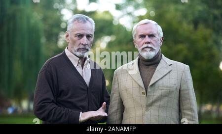 Retired men sadly looking in camera, poor quality of living for pensioners Stock Photo