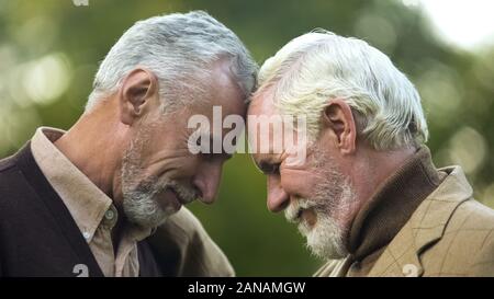 Aged brothers touching heads, family connection, friendship support, buddy Stock Photo