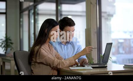 Female and male co-workers reading email laptop, planning strategy, discussion Stock Photo