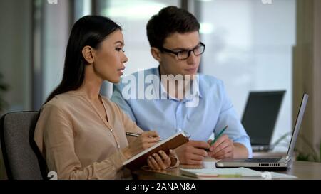 Young colleagues watching online training laptop making notes, planning strategy Stock Photo