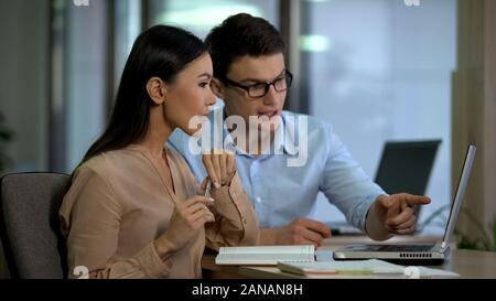 Professional crisis managers sitting front laptop, discussing company strategy Stock Photo