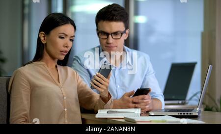 Two colleagues testing work of new mobile app smartphone, software engineering Stock Photo