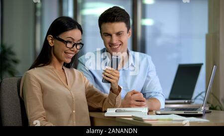 Happy asian caucasian colleagues reading mail on gadget, receiving good news Stock Photo