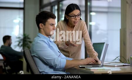 Two colleagues working on laptop, team cooperation on web development project Stock Photo