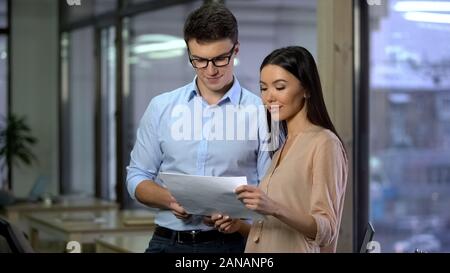 Two business colleagues holding papers in hand, examining company report, work Stock Photo