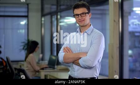 Young company manager crossed arms smiling on camera, professional office worker Stock Photo