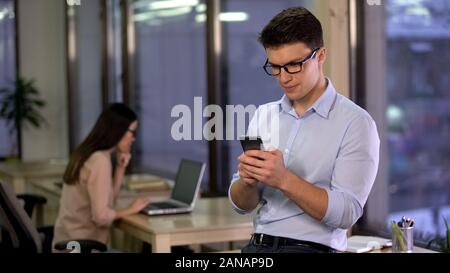 Office employee chatting in social media messenger on smartphone, communication Stock Photo