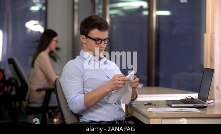 Playful male making paper plane in office, tired monotonous routine work, break Stock Photo