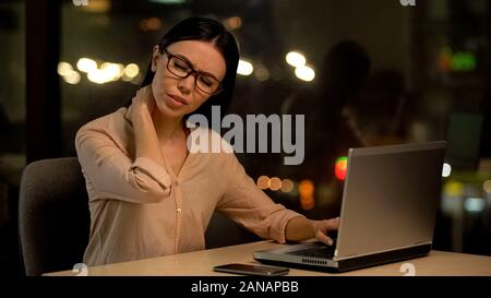 Woman suffering neck pain after working on laptop for long period, muscle strain Stock Photo