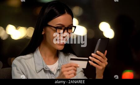 Smiling female shopping online by smartphone, financial application, banking Stock Photo