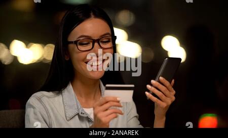 Happy asian lady holding credit card and smartphone, online payment, technology Stock Photo