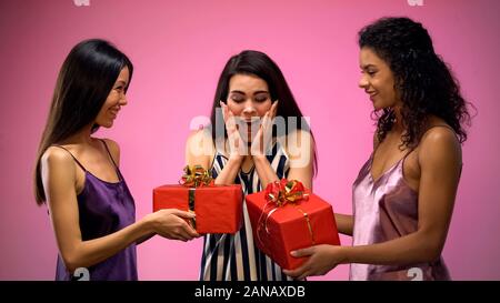 Women giving present to surprised friend, all-girl birthday party, emotions Stock Photo