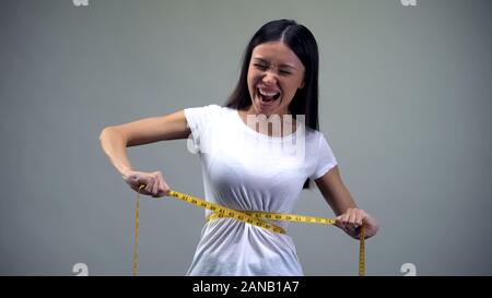 Obsessed woman tightening measuring tape on her waist desire to be slim,  bulimia Stock Photo - Alamy