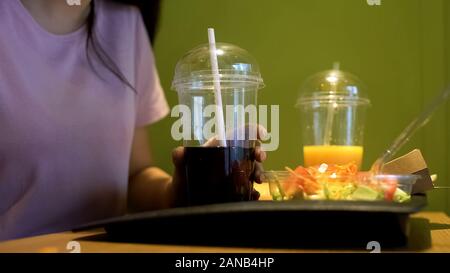 Young woman holding soft drink with straw, student having lunch in cafe, food Stock Photo