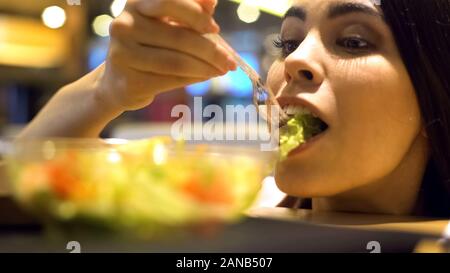 Joyful young lady eating organic lettuce salad in buffet closeup, health care Stock Photo