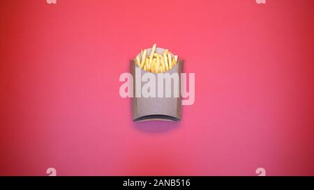 Crispy french fries in carton package on pink background, fast food meal, snack Stock Photo