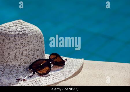 White hat and sunglasses lying beside pool. Summer and holiday concept Stock Photo