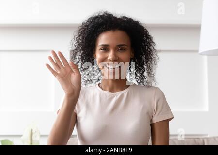 Smiling dark skinned curly lady waving hello. Stock Photo