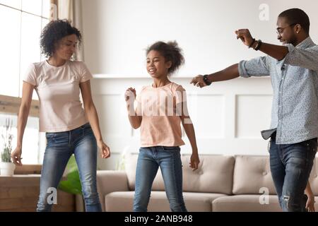 Happy black family dancing in living room. Stock Photo