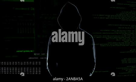 Male silhouette standing against numbers codes after committing cyber crime Stock Photo