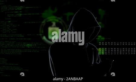 Faceless unrecognizable hooded hacker using smartphone to steal data, cybercrime Stock Photo