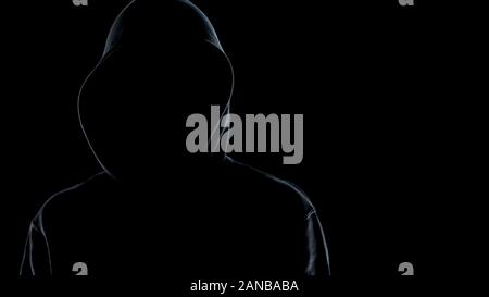 Close up of faceless male silhouette standing against black background, criminal Stock Photo