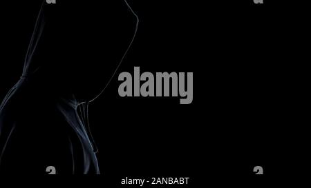 Side view of hooligan silhouette standing against dark background, close up Stock Photo