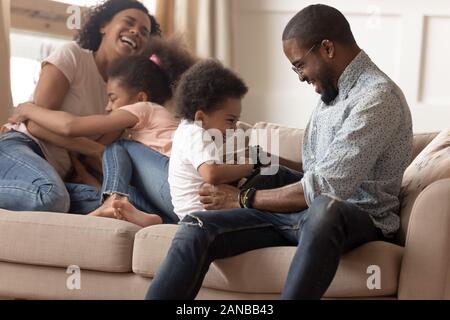 Happy black family with children tickling each other. Stock Photo