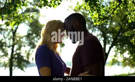 Loving mixed race couple looking at each other and nuzzling, tender feelings Stock Photo