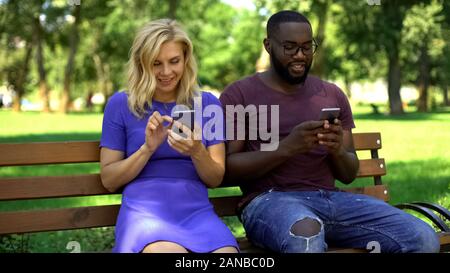 Happy couple absorbed by social media using smartphones instead of interacting Stock Photo