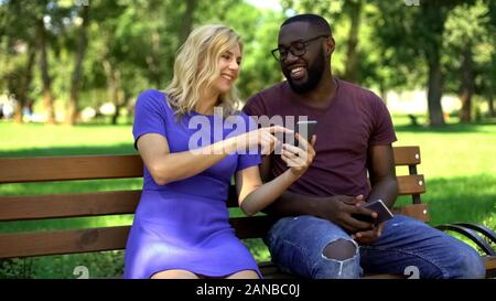 Happy couple watching funny videos in net on smartphone, laughing together Stock Photo