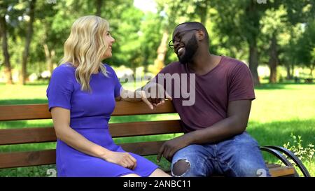 Flirting couple sitting on bench in park, spending time together, happy relation Stock Photo