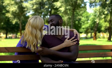 Woman embracing afro-american man from behind, laughing and smiling, surprise Stock Photo