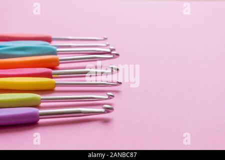 Closeup image of different size colorful crochet hooks on soft pink background Stock Photo