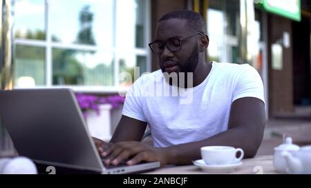 Concentrated student working on university project using laptop, sitting in cafe Stock Photo