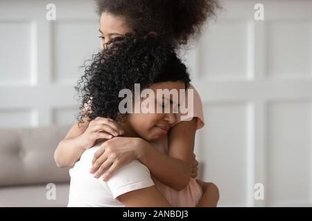 Close up sad upset black woman cuddling daughter. Stock Photo