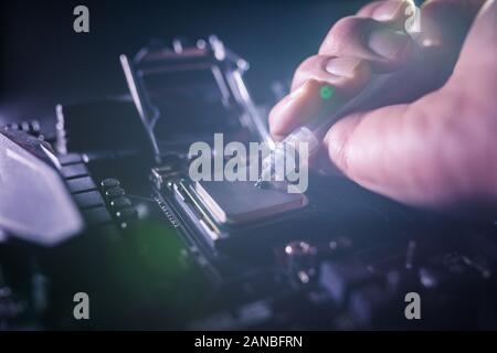 Close up to technician squeezing or application the thermal paste compound on the top of main cpu in the socket. Concept of repairing or upgrading Stock Photo