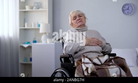 Elderly handicapped woman feeling chest pain, heart arrhythmia, health care Stock Photo
